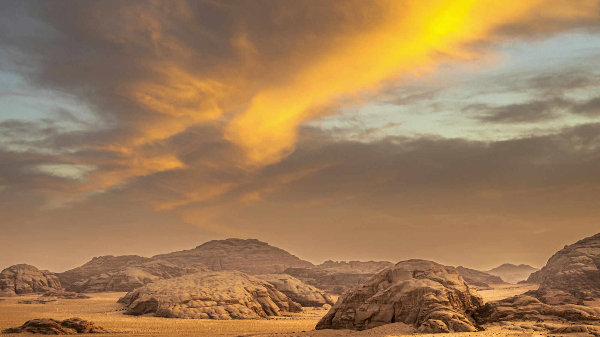 Sculpted desert mountains under a vast, warm evening sky