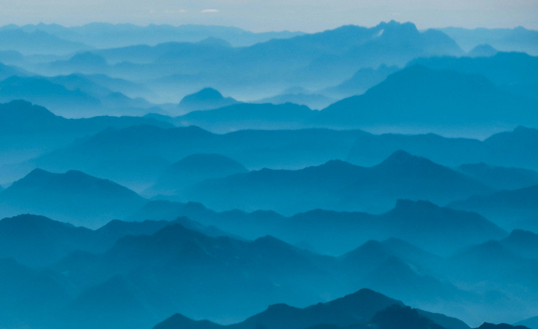Layers of forested mountains fading into blue-green mist